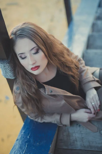 Seductora chica sexy con romántico puchero labios rojos y mejillas meñique usando elegante vestido de chaqueta y pantalones cortos con botas de otoño posando en muelle muelle muelle lado del mar con maquillaje en la cara i episodio romántico — Foto de Stock