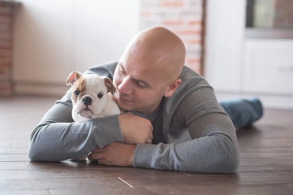 Handsome bold man with puppy english bulldog