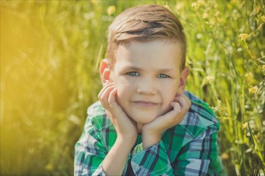 Yakışıklı mutlu çocuk çocuk zevk alan sarı çiçekler rustik köy stil kıyafetlerle tatile yaz saati poz. Şirin çocuk gelecekteki yaşam hakkında rüya