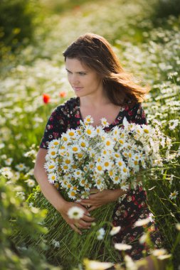 Büyüleyici çok güzel genç bayan kadın koyu esmer saçlar ve yeşil gözlü seksi poz üzerinde şık elbise yabani papatya papatya baş üst ve büyük buket çiçek çelenk ile ihale.