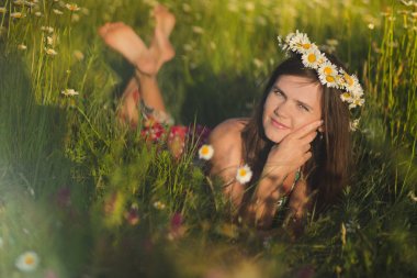 Büyüleyici çok güzel genç bayan kadın koyu esmer saçlar ve yeşil gözlü seksi poz üzerinde şık elbise yabani papatya papatya baş üst ve büyük buket çiçek çelenk ile ihale.