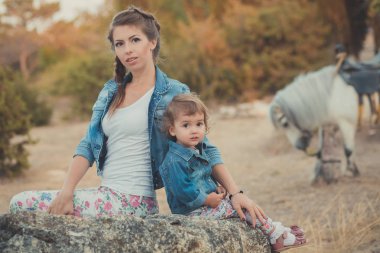 Romantik bir sahne güzel Bayan genç anne şirin bebek kızıyla birlikte zevk zaman birlikte şehir köy park yürüme beslenme beyaz at midilli içinde