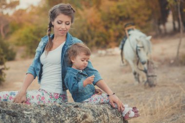 Romantik bir sahne güzel Bayan genç anne şirin bebek kızıyla birlikte zevk zaman birlikte şehir köy park yürüme beslenme beyaz at midilli içinde