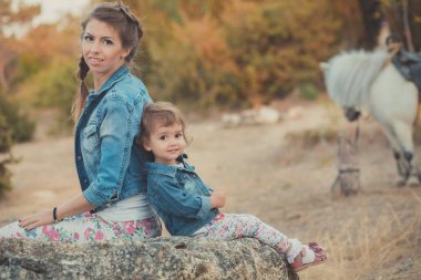 Romantik bir sahne güzel Bayan genç anne şirin bebek kızıyla birlikte zevk zaman birlikte şehir köy park yürüme beslenme beyaz at midilli içinde