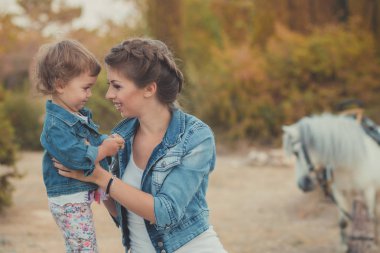 Romantik bir sahne güzel Bayan genç anne şirin bebek kızıyla birlikte zevk zaman birlikte şehir köy park yürüme beslenme beyaz at midilli içinde