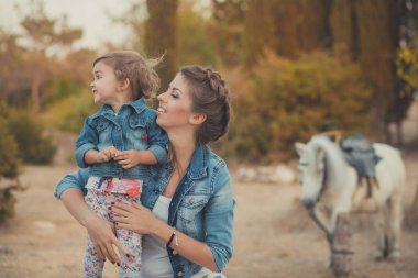 Romantik bir sahne güzel Bayan genç anne şirin bebek kızıyla birlikte zevk zaman birlikte şehir köy park yürüme beslenme beyaz at midilli içinde