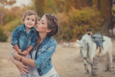 Romantik bir sahne güzel Bayan genç anne şirin bebek kızıyla birlikte zevk zaman birlikte şehir köy park yürüme beslenme beyaz at midilli içinde