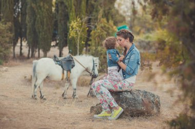 Romantik bir sahne güzel Bayan genç anne şirin bebek kızıyla birlikte zevk zaman birlikte şehir köy park yürüme beslenme beyaz at midilli içinde