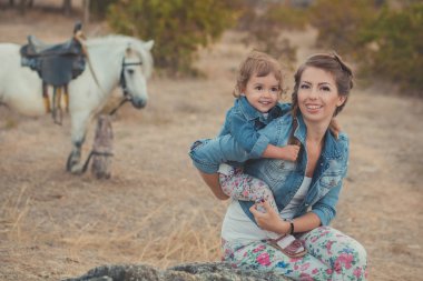 Romantik bir sahne güzel Bayan genç anne şirin bebek kızıyla birlikte zevk zaman birlikte şehir köy park yürüme beslenme beyaz at midilli içinde