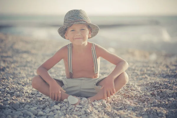 Милий старий хлопчик на пляжі ходить позуючи в вишуканих шортах з шибеницями та джентльменським капелюхом насолоджуйтесь літнім часом наодинці на чудовому океані з якорем. Чарівна сцена дитячого життя — стокове фото