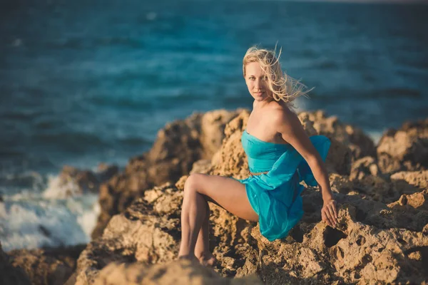 Mujer dama rubia seductora con piernas desnudas sexy hombros y brazos usando vestido abierto azul claro posando disfrutando de tiempo de vacaciones en la playa del mar solo solitario . — Foto de Stock