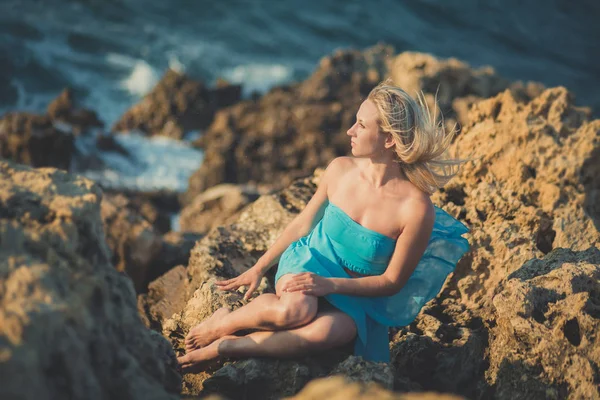 Mujer dama rubia seductora con piernas desnudas sexy hombros y brazos usando vestido abierto azul claro posando disfrutando de tiempo de vacaciones en la playa del mar solo solitario . — Foto de Stock