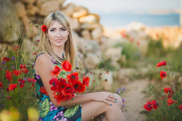 Blond adoreable doamnă femeie purtând rochie elegantă de vară colorată pozând cu corp senzual adorabil pe plaja laterală a mării cu buchet de flori mac roșu — Fotografie, imagine de stoc