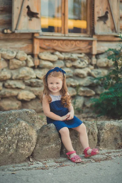 Jonge babymeisje met donkerbruine haren en lichte perfecte huid wangen draagt stijlvolle awesome blauwe jurk poseren met boeket van wild gele bloemen daisy — Stockfoto
