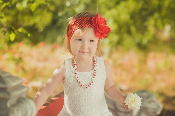Rétro élégant habillé blond jeune fille enfant posant dans le jardin du parc central portant robe blanche couturier français bandana rouge et aumônier — Photo