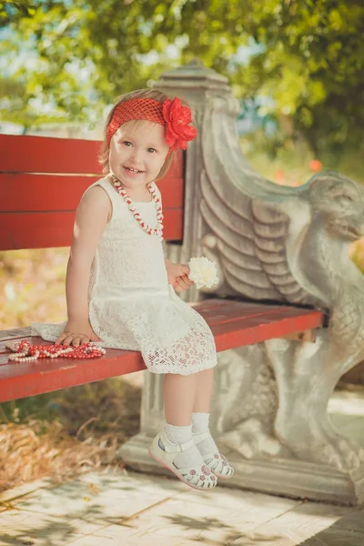 Rétro élégant habillé blond jeune fille enfant posant dans le jardin du parc central portant robe blanche couturier français bandana rouge et aumônier — Photo