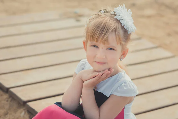 Jeune fille mignonne jouissant de l'heure d'été de l'enfance sur la plage de sable posant sur un pont jetée en bois portant une robe élégante décontractée — Photo