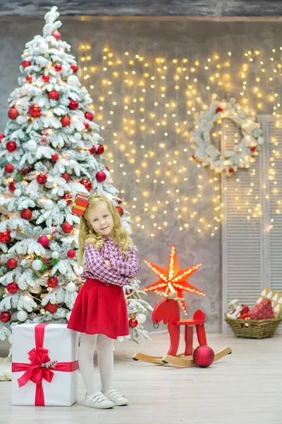 Xmas casual gouden studio kerstversiering met schattig meisje en enorme spiegel met gouden frame genoeg presenteert en grote groene naaldboom — Stockfoto