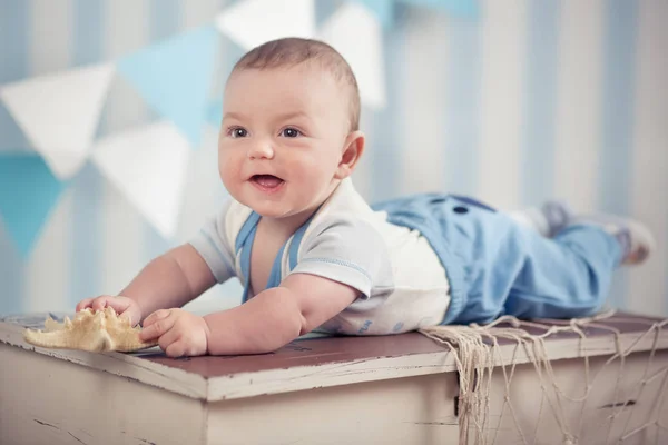 Chłopiec dziecko przystojny śmieszne szczęśliwe dziecko pozowanie na drewnianym stole futro w blue studio — Zdjęcie stockowe
