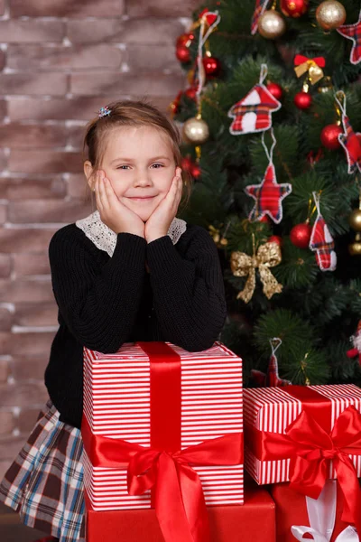 Linda chica dentada con ropa casual elegante feliz disfrutar de vacaciones navideñas cerca de pino verde año nuevo decorado con juguetes acogedores con muchos regalos — Foto de Stock