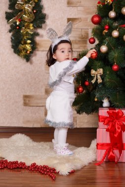 Asya topları oyuncaklar ile yeni yıl Noel yeşil klasik ağacı yakın poz ve renkli gündelik elbise giyen küçük şirin kız sunar. Noel Baba ve çocuk çocuk ile mutlu tatiller