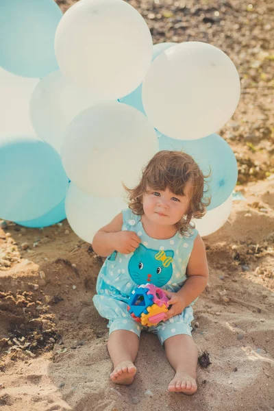 Schattig meisje met blond haar en roze apple Wang genieten van zomertijd vakantie poseren op zand strand zee kant met blauwe witte ballonnen dragen van casual kids kleding — Stockfoto