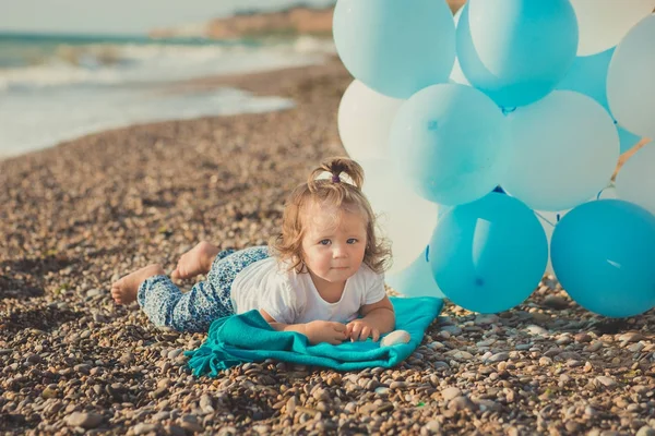 Schattig meisje met blond haar en roze apple Wang genieten van zomertijd vakantie poseren op zand strand zee kant met blauwe witte ballonnen dragen van casual kids kleding — Stockfoto