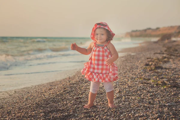 Marvelous dream picture of baby girl with blond hairs blue eyes and pink cheeks posing running on sand beach sea side wearing retro old style colourful clothes — Stock Photo, Image