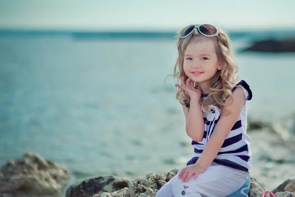 Stílusos felöltözve szőke gyermek lány élvezze a nyaralás pózol a nyilvános városi strand ruhában alkalmi fényes boldog, mosolyog a kamera egyedül — Stock Fotó