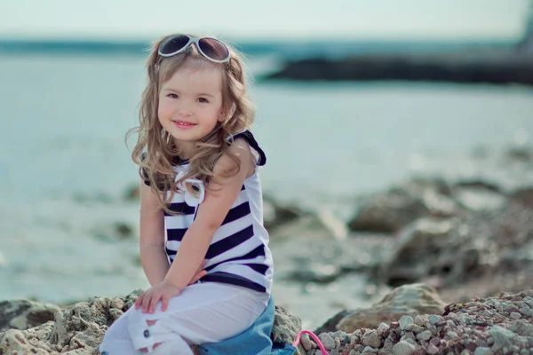 Şık giyinmiş sarışın çocuk kız zevk yaz tatili yalnız kameraya gülümseyen mutlu rahat parlak kıyafetleri genel şehir sahilde poz