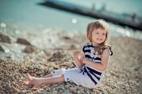 Stylish dressed blond child girl enjoy posing summer vacation on public city beach wearing casual bright clothes happy smiling on camera alone — Stock Photo, Image