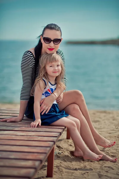 Trendy mother with black hairs and red lips in sun glasses enjoy summer time on a beach with her baby daughter ,Adorable scene of woman family love — Stock Photo, Image