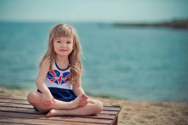 Stylish dressed blond child girl enjoy posing summer vacation on public city beach wearing casual bright clothes happy smiling on camera alone — Stock Photo, Image