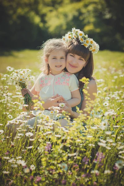 Feliz bela mãe senhora posando com sua filhinha fofa em linda cena da vida de verão da família no prado de flores de papoula margarida juntos — Fotografia de Stock