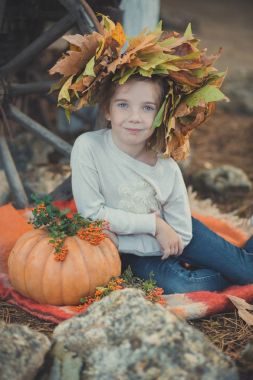 Bebek öpebileceğinize örgü saçlı ve beyaz elbise gömlek giymiş ve kabak yakın kırmızı kareli kameraya bakarak sonbahar yaprakları wreathon kafa ile poz çillenmesi yanak mavi gözlü genç kız