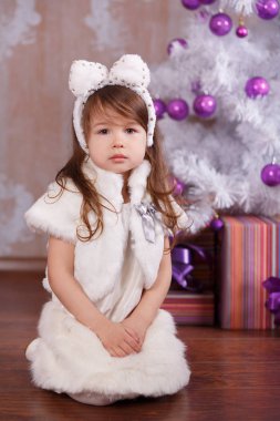 Beyaz elbise kürk ceket askısı ve stüdyo Kış Noel ağacı içinde poz gülümseyen ayakkabılar pout dudak ve pembe yanakları ile sunar rahat akşam resmi genç esmer dolly Bayan kız şık giyinmiş.