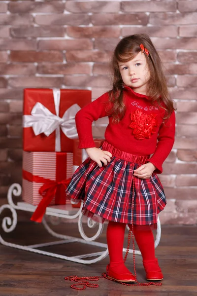 Jovem morena dolly menina elegante vestida com chequers de camisola pulôver vermelho verificar tartan saia alça sapatos sorrindo posando sentado em estúdio inverno trenó jumper com lábios de faneca e bochechas rosa . — Fotografia de Stock