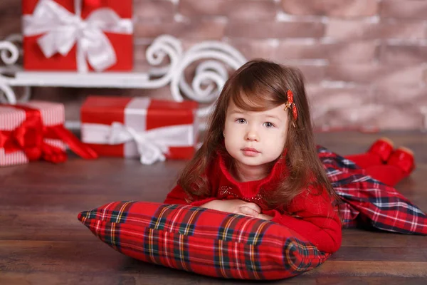 Joven morena muñeca dama chica elegante vestido con traje rojo chequers comprobar tartán falda correa zapatos sonriente posando sentado en el estudio árbol de Navidad con los labios de la puchera y mejillas de color rosa . — Foto de Stock
