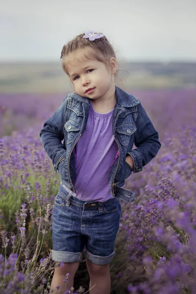 Bellissima bionda carina Giovane ragazza di bellezza in jeans blu e camicia viola in posa per la fotocamera con un sorriso accogliente face.Wellbeing tempo trascorso nei campi del villaggio di lavanda in agosto Francia Provenza — Foto Stock