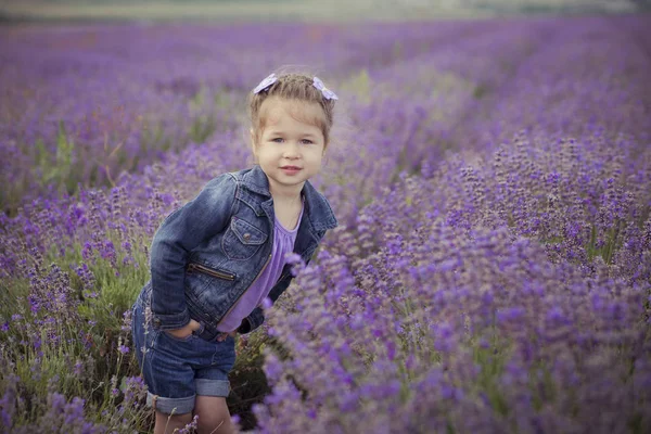 Gyönyörű aranyos szőke fiatal szépség lány farmer kék és lila póló, pózol a kamera hangulatos mosollyal arcán. A falu mezők a levendula augusztus Franciaország-Provence-ban jólét eltöltését — Stock Fotó