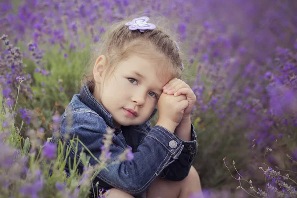 Close portrait of beautifull cute blond Young girl in blue jeans and purple shirt posing to camera with happy smile face.Wellbeing time spending in village fields of lavender in august France Provence — стоковое фото