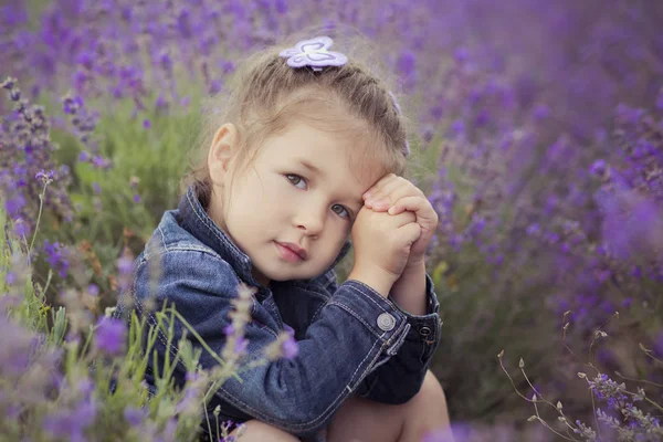 Nära porträtt av Beautifull Söt blond ung flicka i blå jeans och lila skjorta poserar för kameran med lyckligt leende ansikte. Välbefinnande tid tillbringar i byn fält av lavendel i augusti Frankrike Provence — Stockfoto