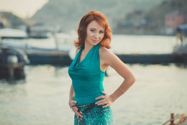 İnanılmaz güzel hanımefendi kadın kız ahşap iskele iskele wth bağlantı noktası tekne deniz deniz kızı arka plan Adoring sahne üzerinde oturan poz alev kırmızı saç giyen moda yeşil giysileri ile