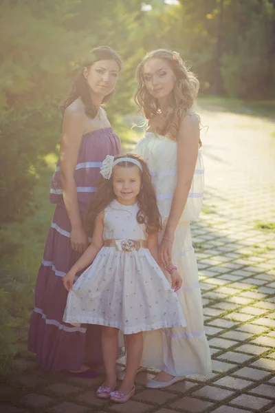 Utrolige brunette, blonde kastanjeblå øyne, jenter med stilig, hvit, lilla kjole, som nyter ferien sammen, solskinnsdag, i en eng på nytt gress, nydelig smil. – stockfoto