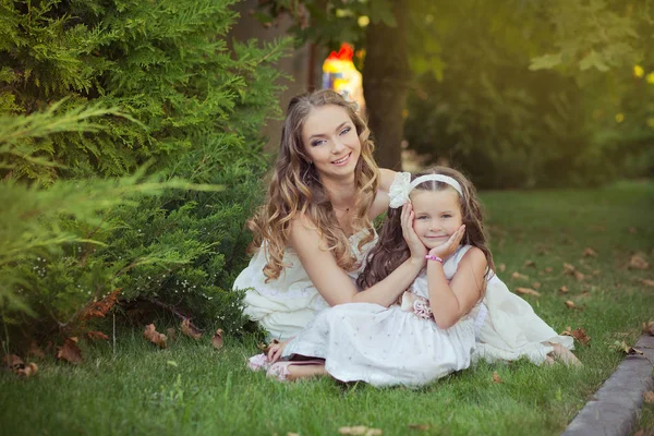 Deux sœurs blondes châtaignier yeux bleus dames filles posant ensemble été ensoleillé jour soir habillé en blanc aéré dîner fête vêtements formels sur herbe fraîche printemps jardin — Photo