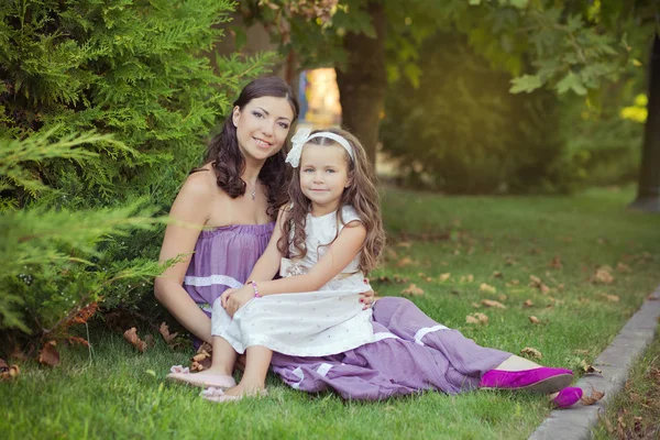 Two sisters friends chestnut brunette blue eyes woman girls posing together summer sunny day evening dressed in white purple airy dinner party formal clothes on fresh spring grass garden happy smiling — Stock Photo, Image
