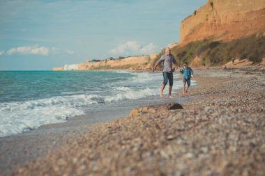 Baba ve oğlu deniz kıyısı yürüyüş. Baba ve oğul okyanus kıyı yürüyüş. Hafta sonu sahile. Bir plaj taş. Deniz köpüğü.