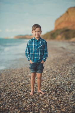 Plajda tek başına duran mutlu çocuk portresi