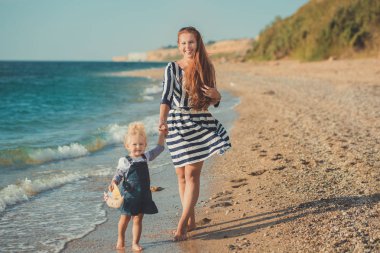 Güzel annesi Bayan plaj deniz yan stylush sevimli kız ile giyinmiş.