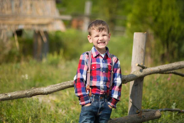 Niedlichen Fermer gutaussehenden Jungen Cowboy in Jeans genießen Sommertag im Dorfleben mit Blumen tragen ledernen Kuhhut glücklich lächelnd. — Stockfoto